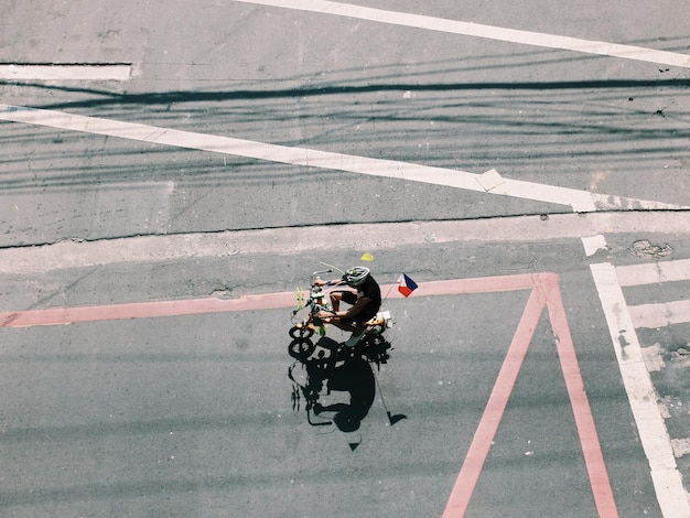 Foto vista ad alto angolo di un uomo con la bandiera filippina che va in bicicletta sulla strada