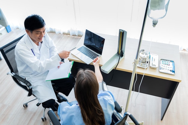 High angle view of mature doctor talking to female patient in clinic