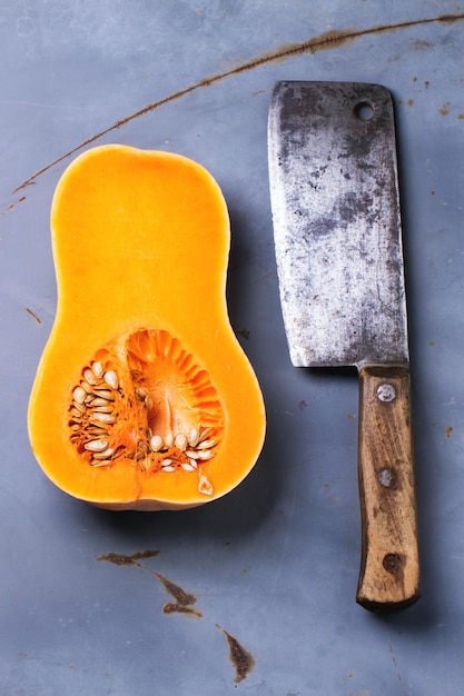 High angle view of meat cleaver and butternut on rusty metallic table
