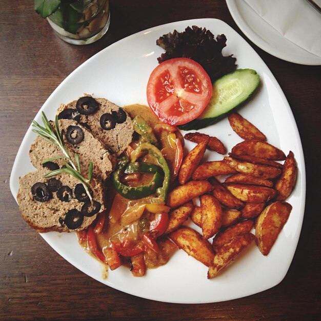 High angle view of meat loaf served with fried potatoes and salad in plate