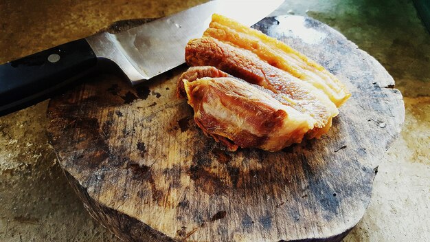 Foto vista ad alto angolo della carne con un coltello da cucina su un tavolo da taglio in legno