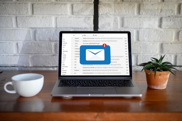 Photo high angle view of message symbol on laptop screen by potted plant at table