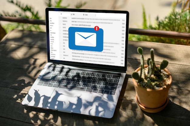 High angle view of message symbol on laptop screen by potted plant at table