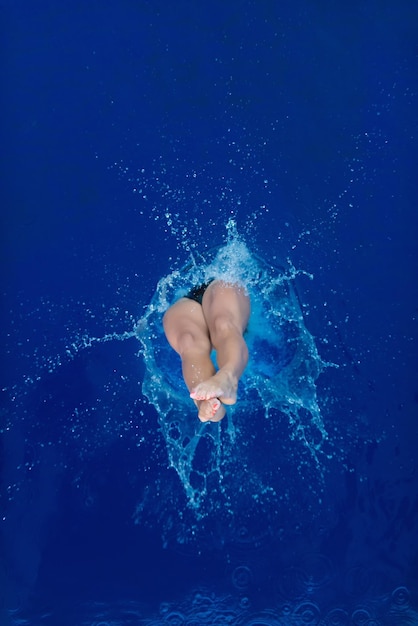 High angle view of mid adult woman wearing bikini while jumping in swimming pool
