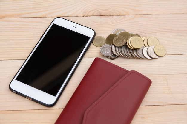 Foto vista ad alto angolo del telefono cellulare con monete e portafoglio sul tavolo