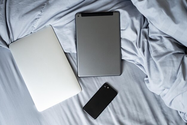 Photo high angle view of mobile phone with digital tablets on bed