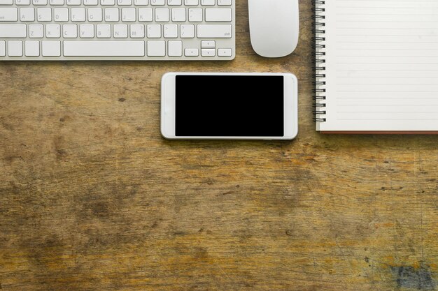 Photo high angle view of mobile phone with keyboard and book on wooden table