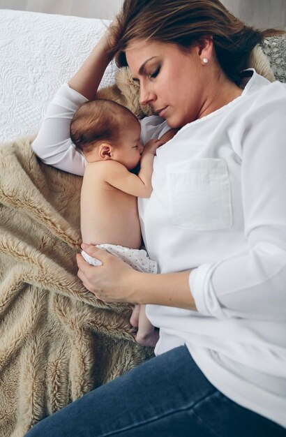 Foto vista ad alto angolo di madre che allatta la figlia mentre giace a letto a casa