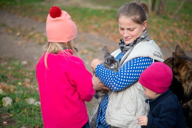 Foto vista ad alto angolo di una madre che porta un coniglio mentre è in piedi con i bambini nel parco