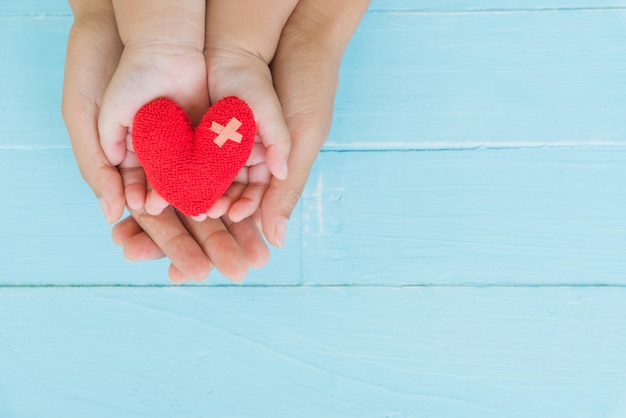 High angle view of mother and child holding red heart shape toy on table