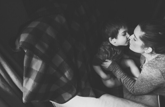 Photo high angle view of mother kissing son sitting on chair at home