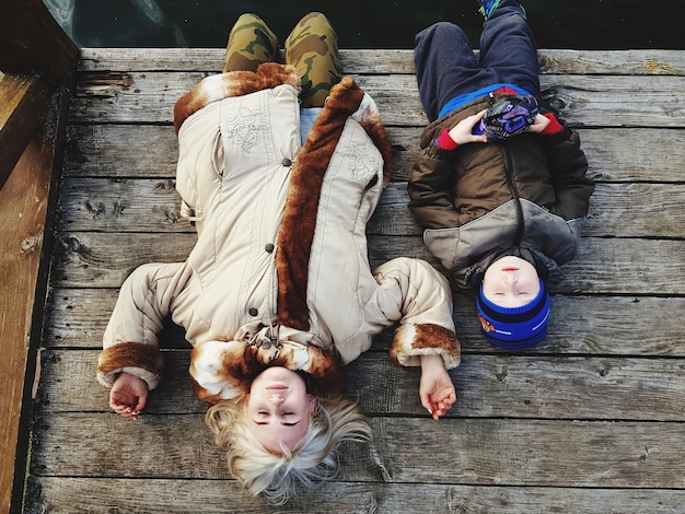 high angle view of mother and son lying on wooden pier