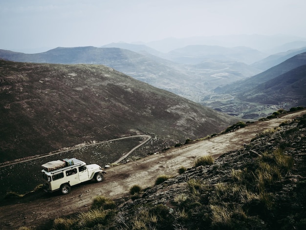 High angle view of mountain dirt road and 4x4 vehicle amidst dark landscape against sky lesotho africa