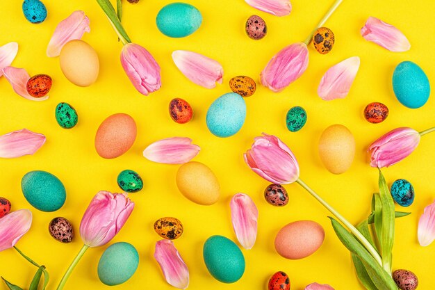 High angle view of multi colored quail eggs and flowers against yellow background