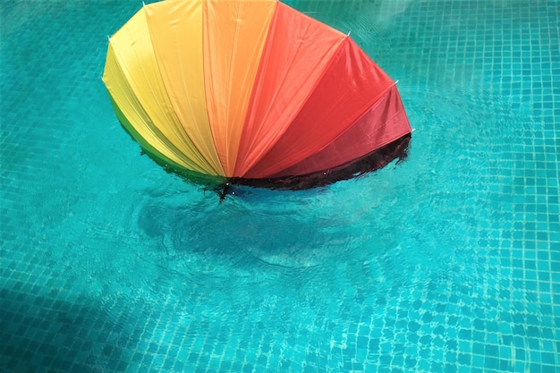 Foto vista ad alto angolo di un ombrello multicolore che galleggia sulla piscina