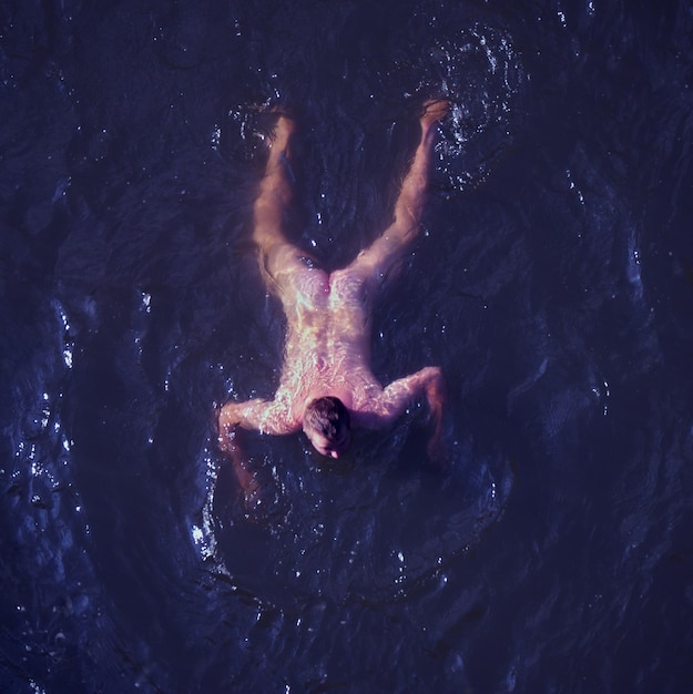 Foto vista ad alta angolazione di un uomo nudo che nuota nel lago