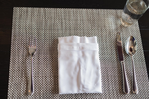 High angle view of napkin with cutlery on place mat at dining table