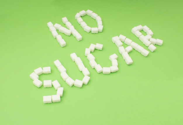 Photo high angle view of no sugar text made with food over green background