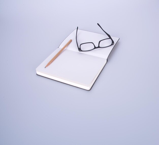 Фото Высокоугольный вид пустой книги с очками и карандашом на белом фоне