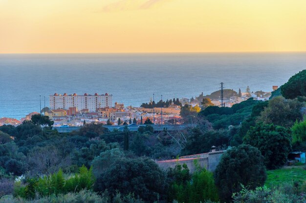 写真 夕暮れの空を背景にした建物と海の高角度の景色