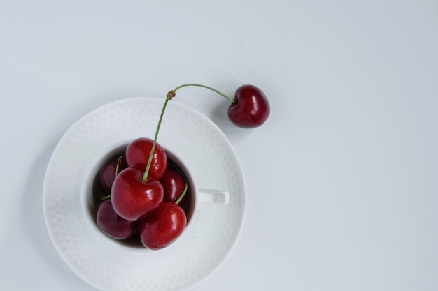 Фото Высокоугольный вид вишни на тарелке на белом фоне