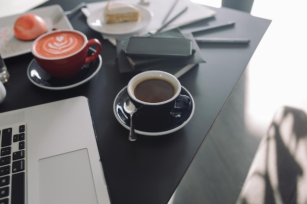 Фото Высокоугольный вид кофейных чашек с помощью ноутбука на столе