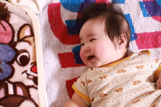 写真 ベッドに横たわっている可愛い笑顔の赤ちゃんの高角度ビュー