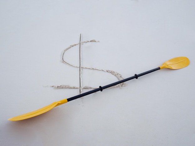 Фото Высокоугольный вид знака доллара и весла на песке