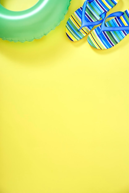Фото Высокоугольный вид флип-флопсов и надувного кольца на желтом фоне