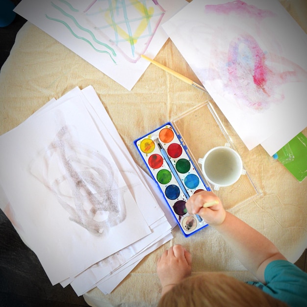 写真 机の上で水彩画で遊んでいる女の子の高角度の視点