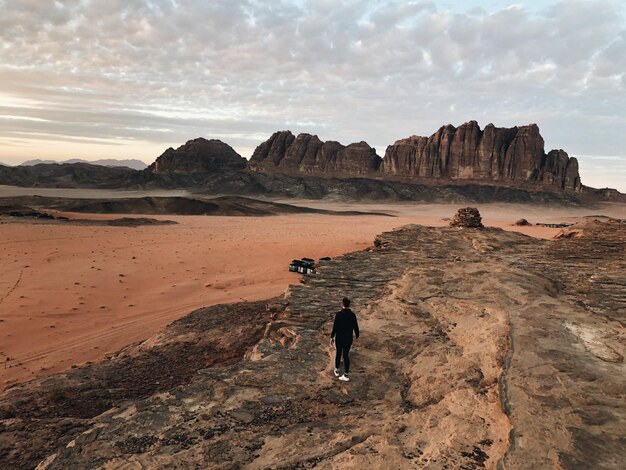 写真 荒れ果てた風景を眺める岩層の上に立っている男の高角度の景色