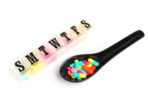 Фото Высокоугольный вид многоцветных таблеток в ложке с текстом на белом фоне