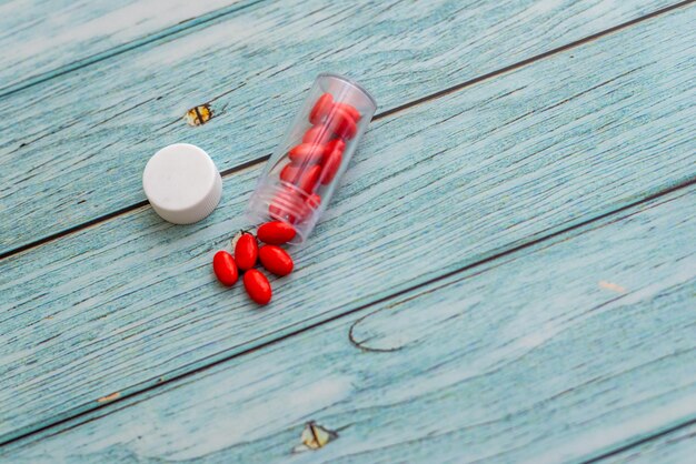 Фото Высокоугольный вид красных таблеток и бутылки на столе