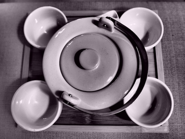 Фото Высокоугольный вид чайника с пустыми чашками на столе