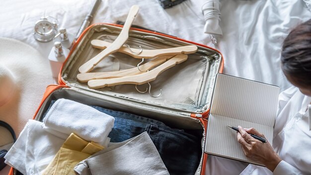Фото Высокоугольный вид женщины, упаковывающей чемодан на кровати