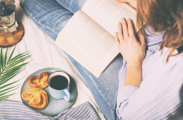 사진 침대에 아침 식사를 하면서 책을 읽는 여성의 높은 각도 시각