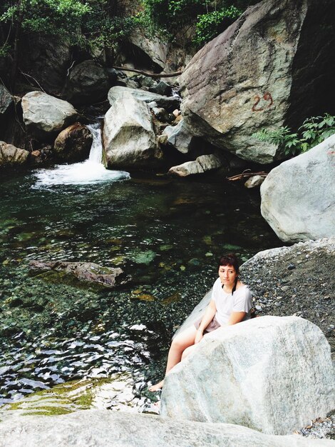 写真 川のそばの岩の上に座っている女性の高角度の景色