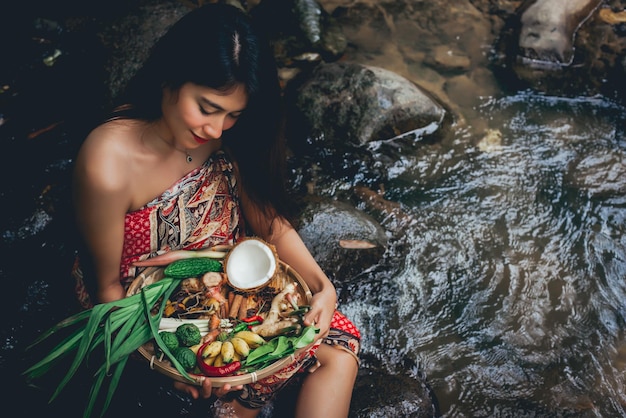 写真 川の岩の上に食べ物を持って座っている女性の高角度の景色