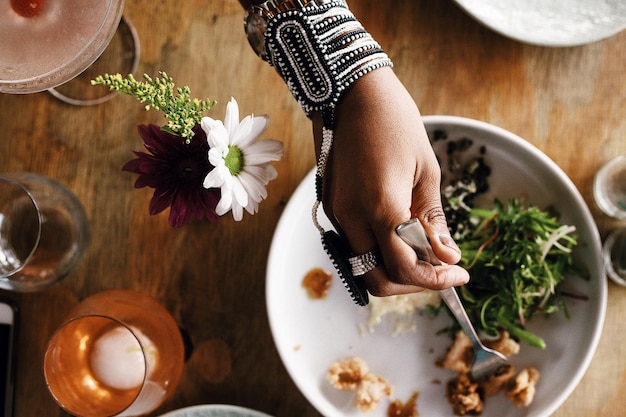 写真 テーブルの上に食べ物を握っているアフリカの宝石を身に着けた女性の高角度の写真