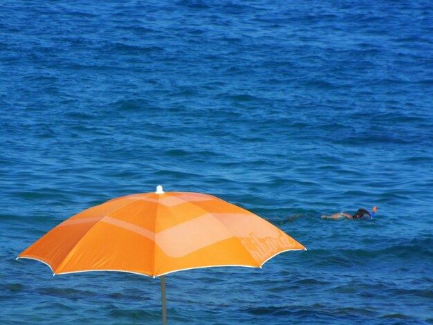 Foto vista ad alto angolo di un ombrello arancione contro il mare