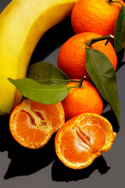 Foto vista ad alto angolo di arance con banane su sfondo nero