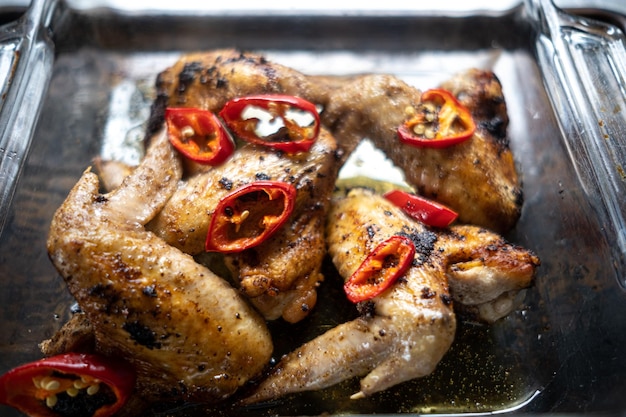 Foto vista ad alta angolazione delle ali di pollo allevate in pascolo biologico grigliate e guarnite con peperoncino