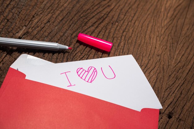 High angle view of paper with in envelope and pen on wooden table