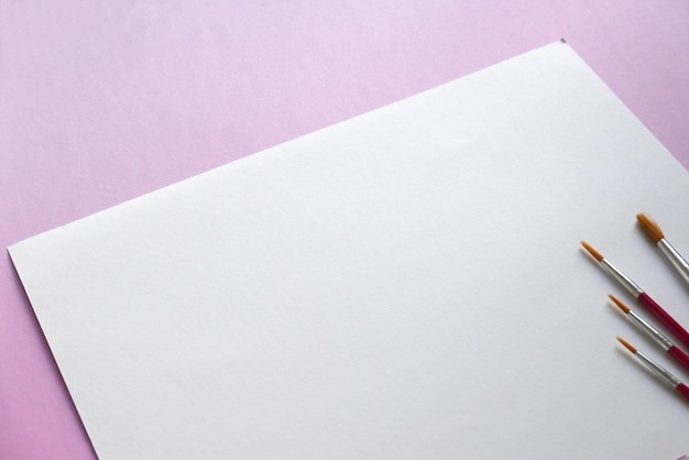 Photo high angle view of paper with paintbrush over pink background
