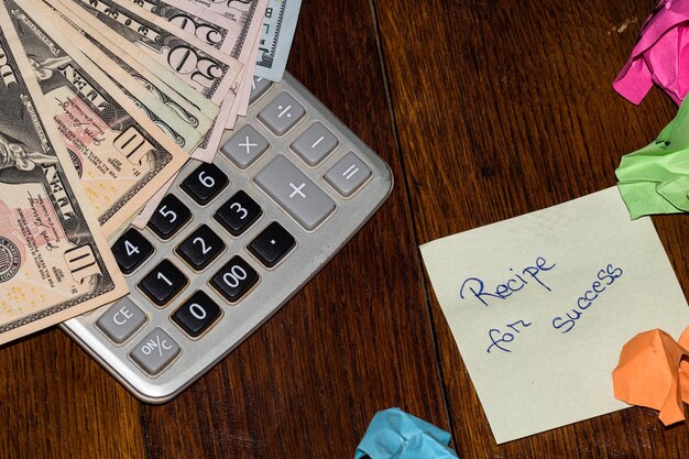 High angle view of paper with text by calculator and currency at table