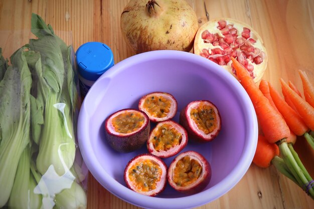 Foto vista ad alto angolo della frutta della passione in una ciotola con le verdure sul tavolo