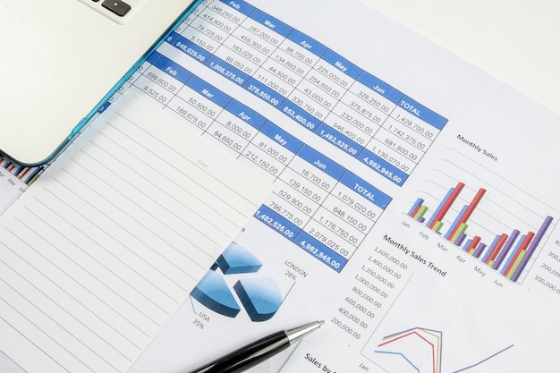 High angle view of pen and financial dosuments with laptop on table