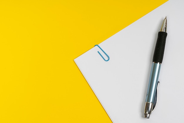 High angle view of pen with paper on yellow background