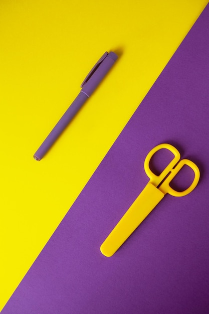 High angle view of pen with scissors on colored background