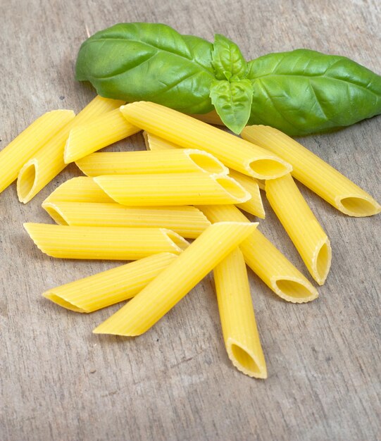 High angle view of penne pasta and basil leaves on table